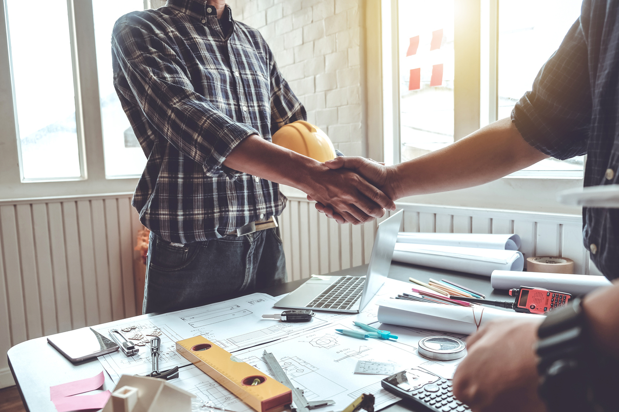 two blue collar workers shaking hands