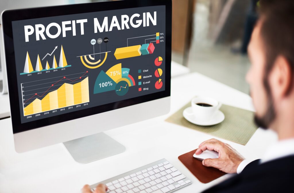man looking at computer that says profit margins on it